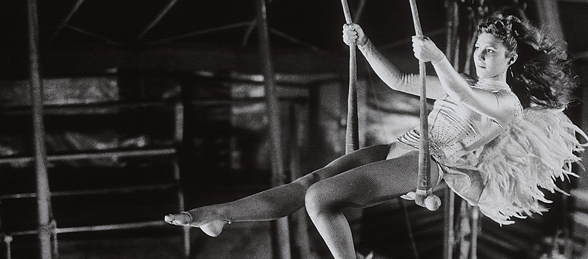 Actress Solveig Dommartin swings on a trapeze in an angel costume in a still from the 1987 Wim Wenders film Wings of Desire