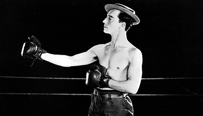 Man in hat poses with boxing gloves in a fighting stance