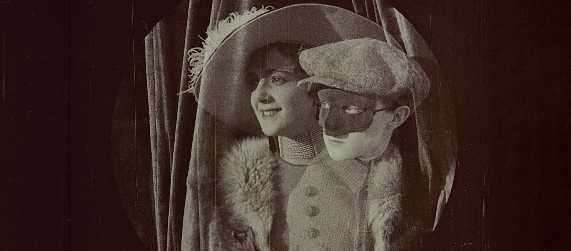A person in disguise peaks over the shoulder of a woman in a big hat