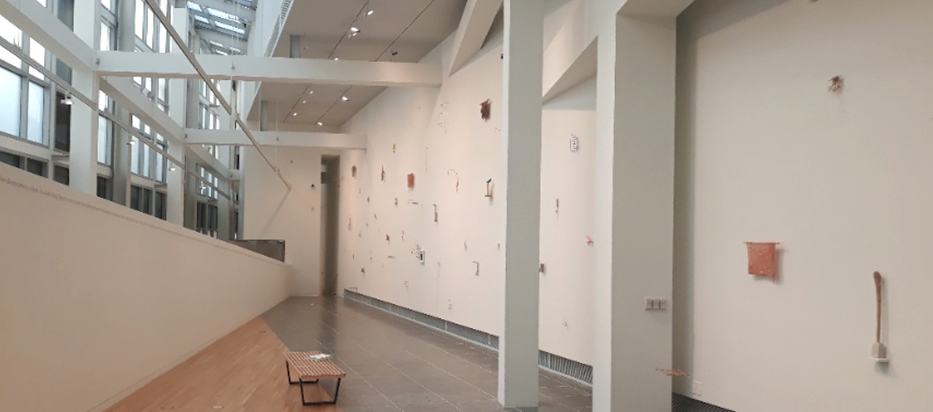 An image shot from above of Gallery B in the Wexner Center for the Arts at The Ohio State University. The image includes the white grid work near the ceiling of the center's galleries and an installation of precarios by artist Cecilia Vicuña.