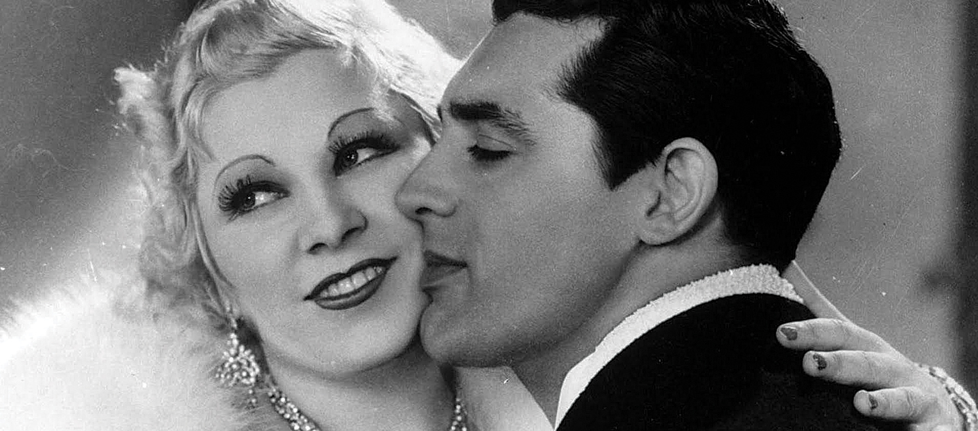 Cary Grant kisses the cheek of a smiling Mae West in a scene from the 1933 film I'm No Angel