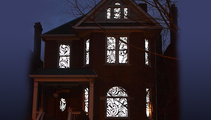 Antique patterns activated by light in the windows of a three-story Victorian home