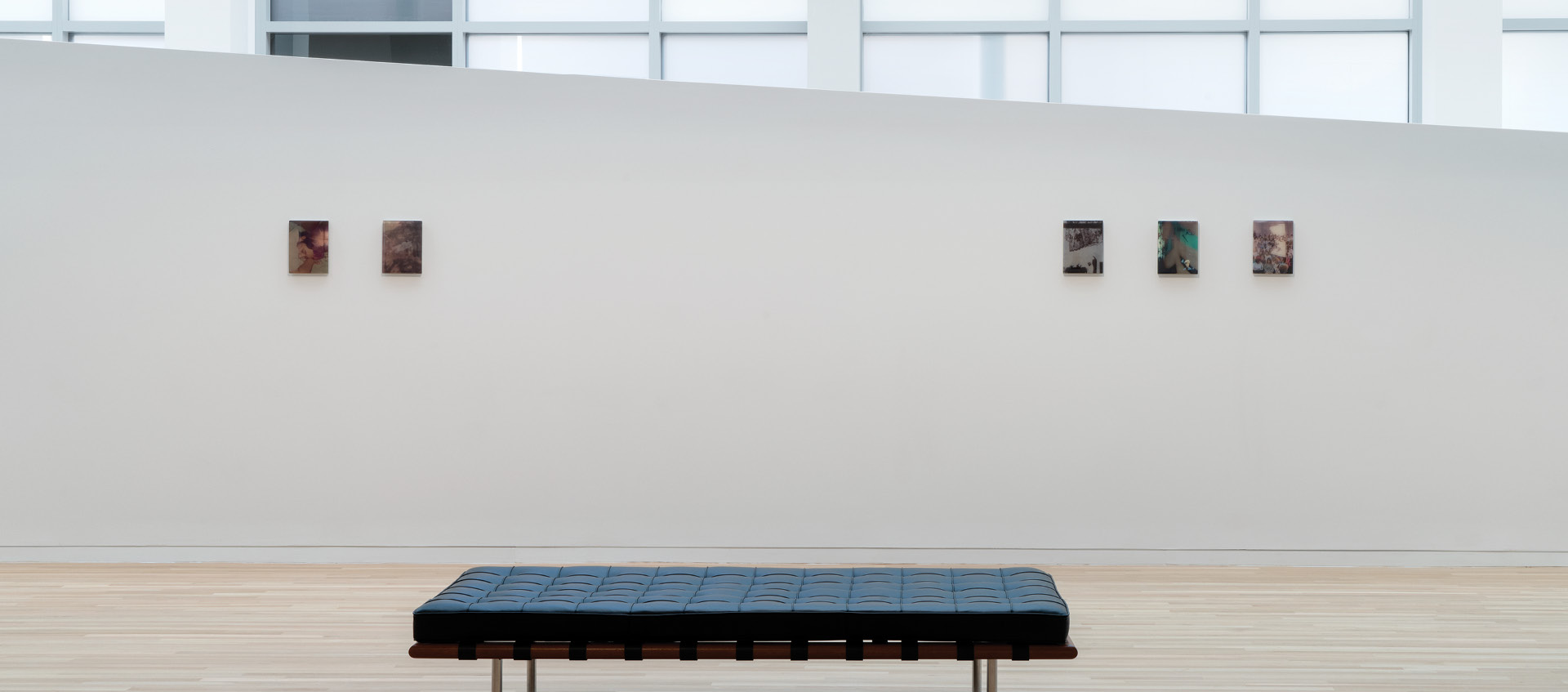 a black bench in front of a white wall with art pieces on it