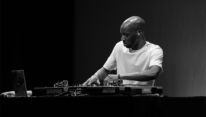 DJ Krate Digga in white T-shirt with hands on music equipment