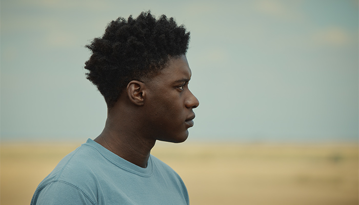 A teenaged Femi, shown in profile, looks off into the distance