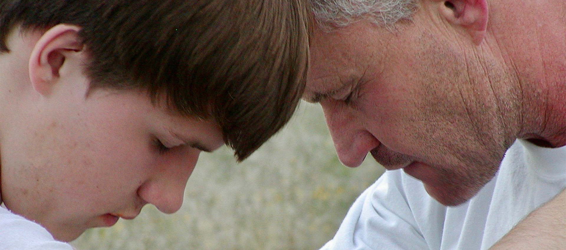 A father and child, Ryan and Rob Robertson, pray together touching foreheads.
