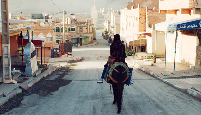 A horse and rider move down a city street in the short film So What If the Goats Die