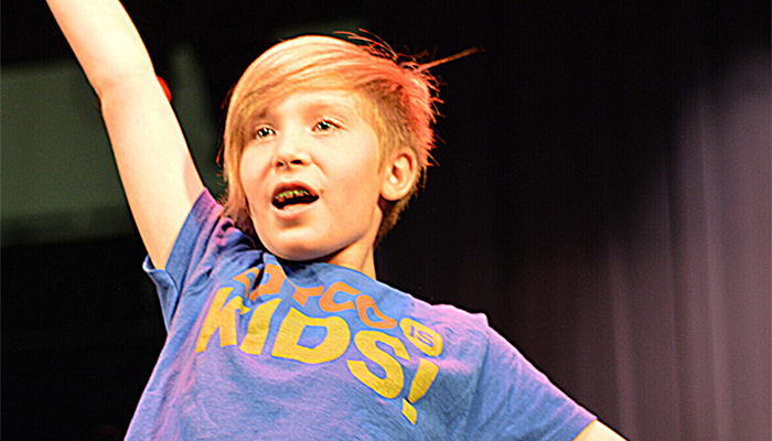 A CATCO youth performer onstage with his right arm raised