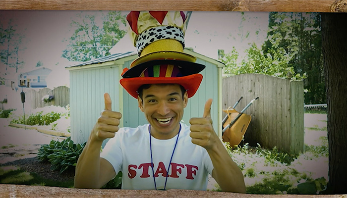 Actor Zachary Noah Piser smiles and wears a pile of hats and gives two thumbs up during an episode of PBS Thirteen's Camp TV