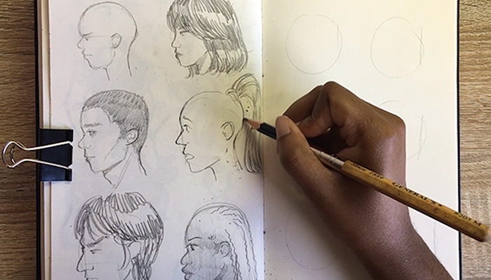 The hand of Columbus artist Joy Annorzie draws a person's profile in her sketch book