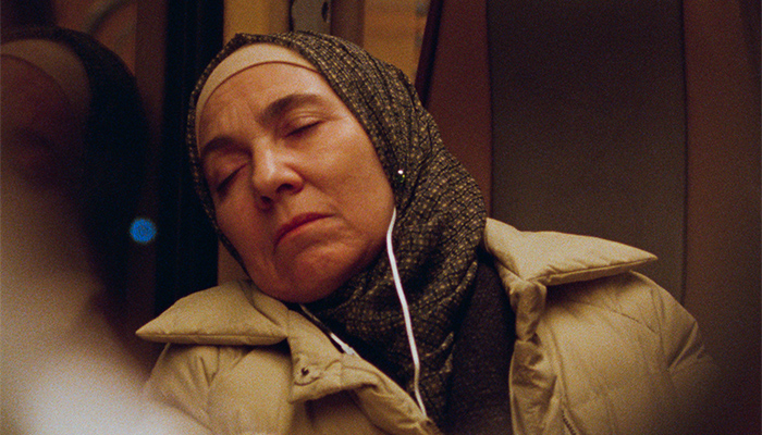 Khadija sleeps on the train with headphones on