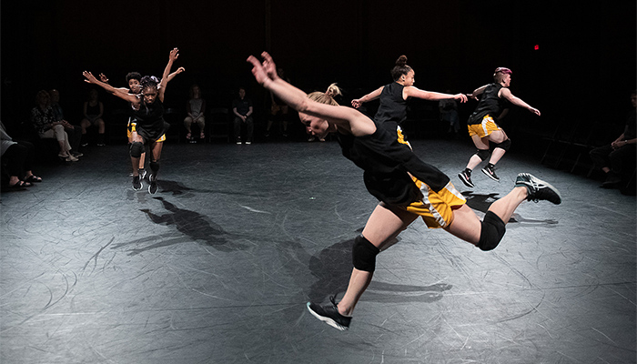 Five dancers moving across the floor