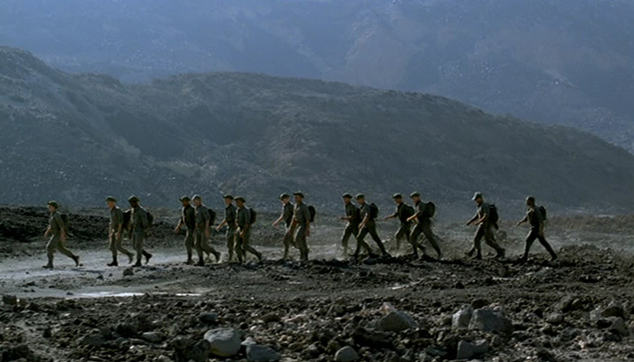 A group of soldiers march on a hillside