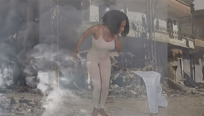 A woman in a white leotard stands in the center of the frame in front of a projected background