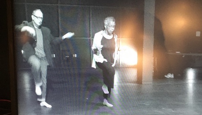 Dancers Paul Lazar and Bebe Miller rehearsing on an empty stage, as seen through a TV monitor