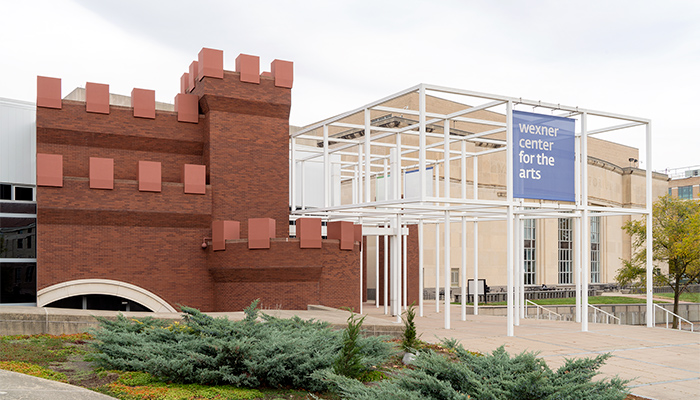 The Wexner Center’s exterior features crenellated, castle-like brick towers and contrastingly spare modular core with a projecting grid-like metal framework.