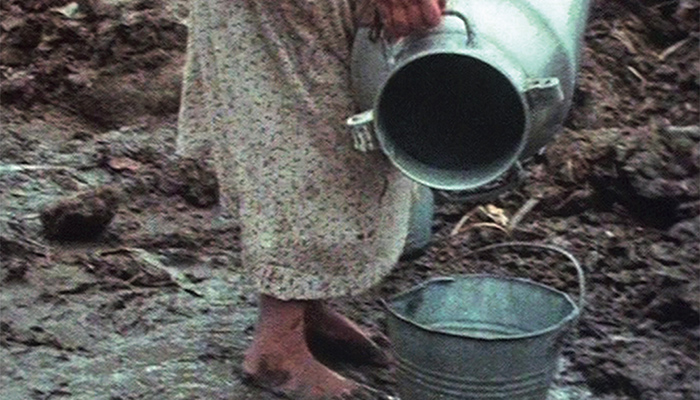 A woman pouring water into a bucket.